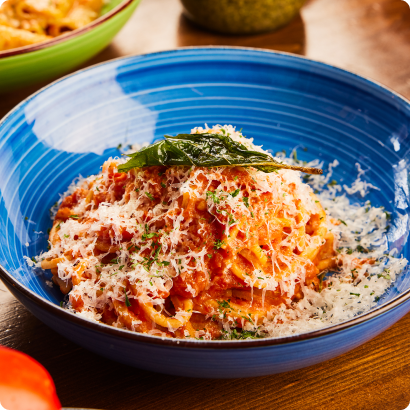 Plate of spaghetti with marinara sauce, garnished with basil and grated parmesan cheese at Mangiare